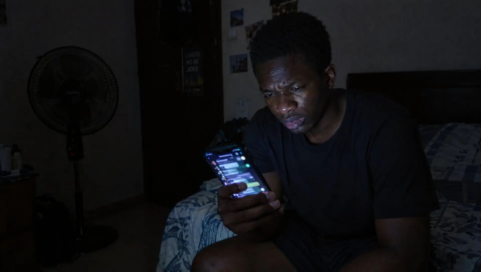 A Nigerian man frowning with doubt at a busy group chat on his phone late at night