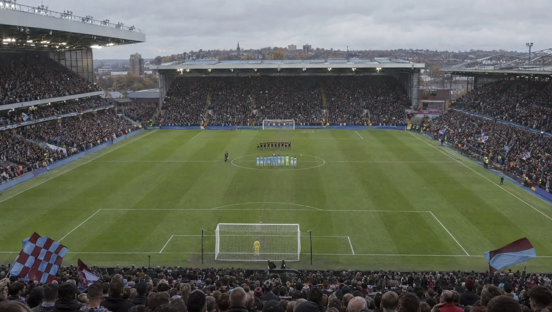 A full English football stadium on matchday with fans in the stands and players on the pitch