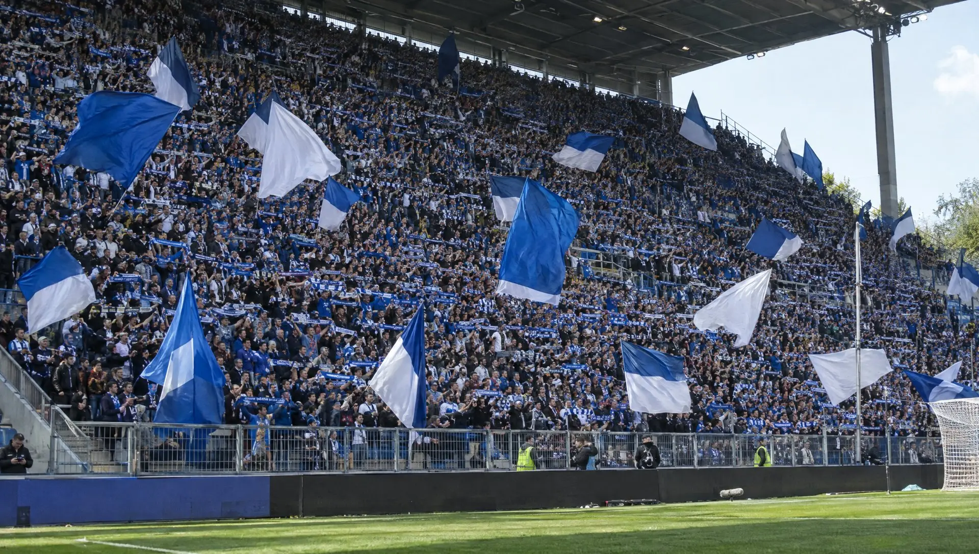 Fans waving scarves in a steep stand at a German football stadium before kick-off