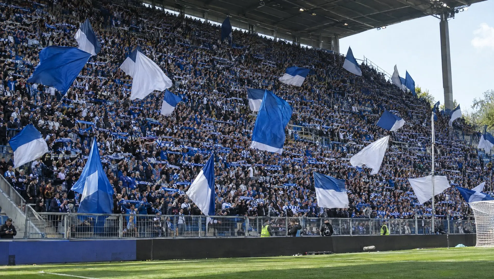Fans waving scarves in a steep stand at a German football stadium before kick-off