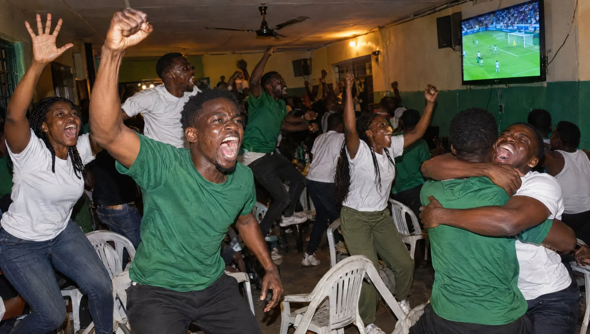Nigerian fans in a Lagos viewing centre jumping to celebrate a goal on the big screen